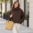 Una mujer usa una chaqueta marrón con capucha y lleva un bolso mostaza de regalo